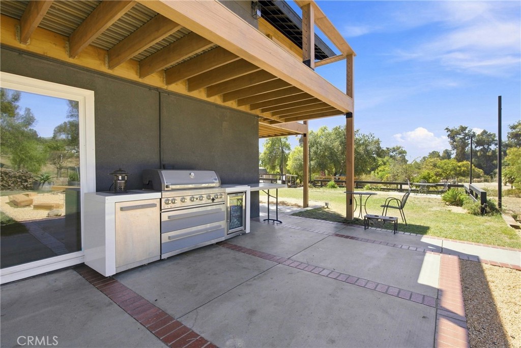 Covered patio with a stainless steel outdoor kitchen and timber deck overlooking the yard.