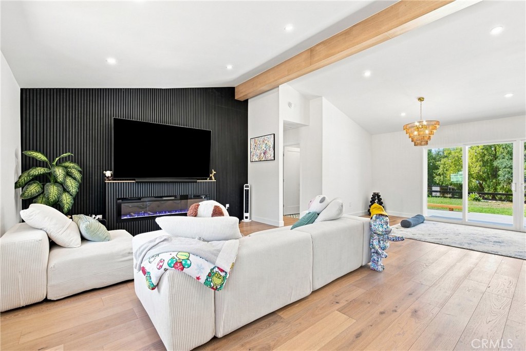 Living room with a white sectional, black media wall, wood floors, and sliding doors to a green yard.