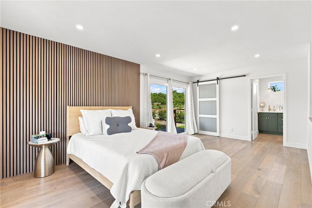 Furnished bedroom with a slatted accent wall, sliding glass doors, and a glimpse of a green bathroom vanity.