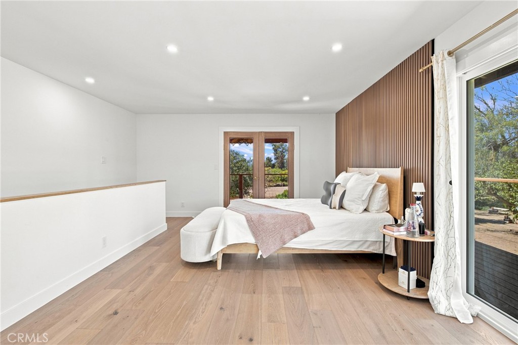 Staged bedroom with a low bed, wood-slat accent wall, and glass patio doors.