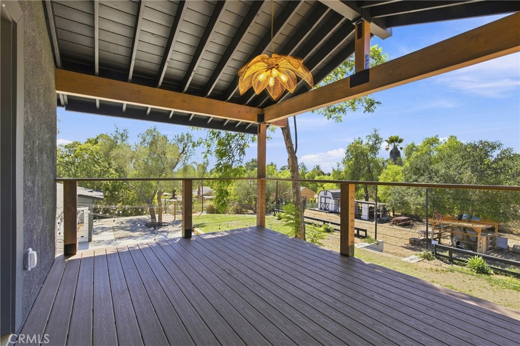 Covered deck with dark flooring and wood beams overlooking a tree-filled yard.