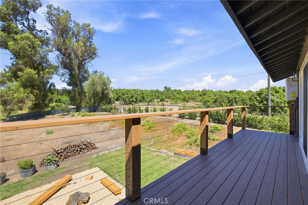 Wooden deck overlooking rows of orchard trees and a dry yard.