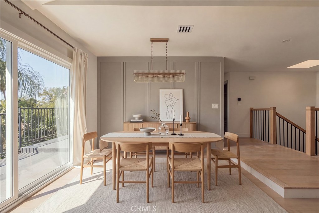 Staged dining room with a light wood table, paneled accent wall, and sliding glass doors to a balcony.