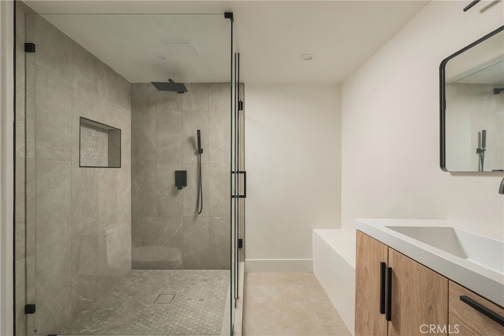 Modern bathroom with a glass walk-in shower and wood-front vanity.