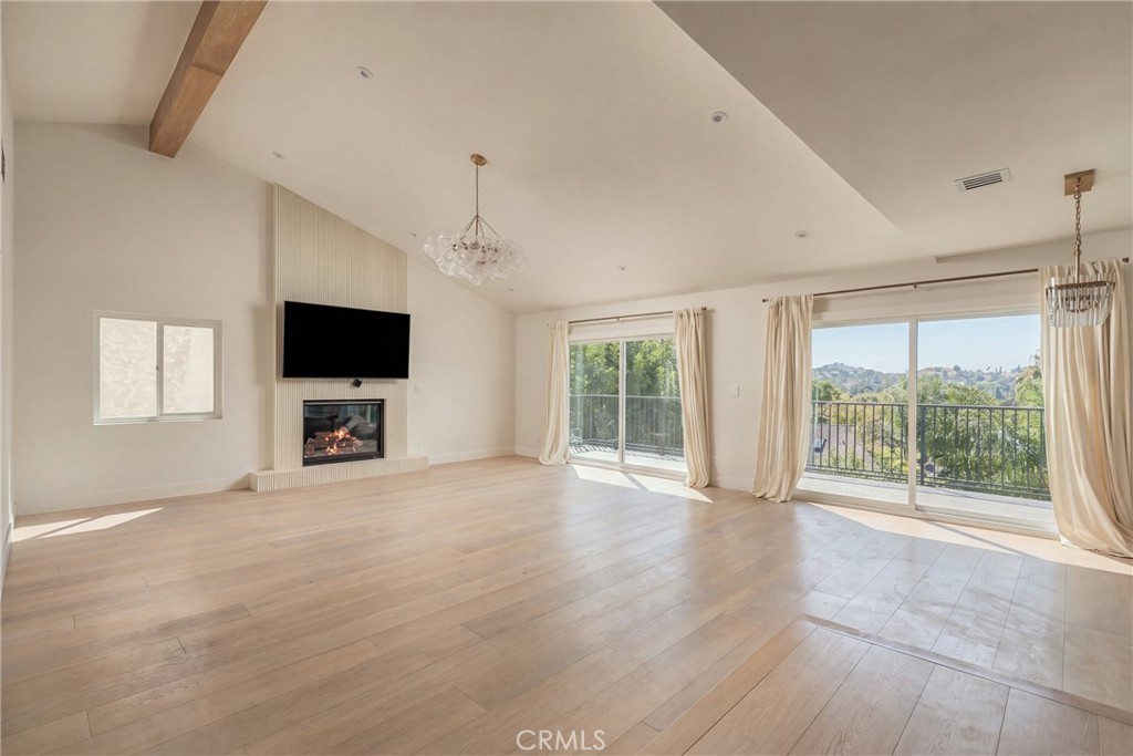 Vacant living room with a fireplace, wall-mounted TV, and sliding doors to a balcony.