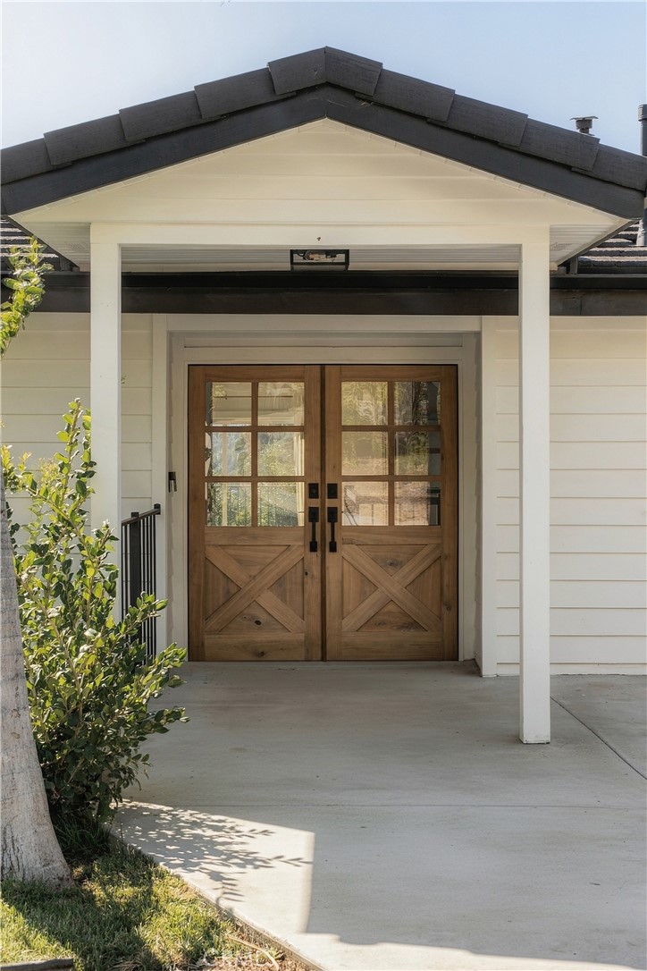 Home entrance with wooden double doors beneath a white covered porch.