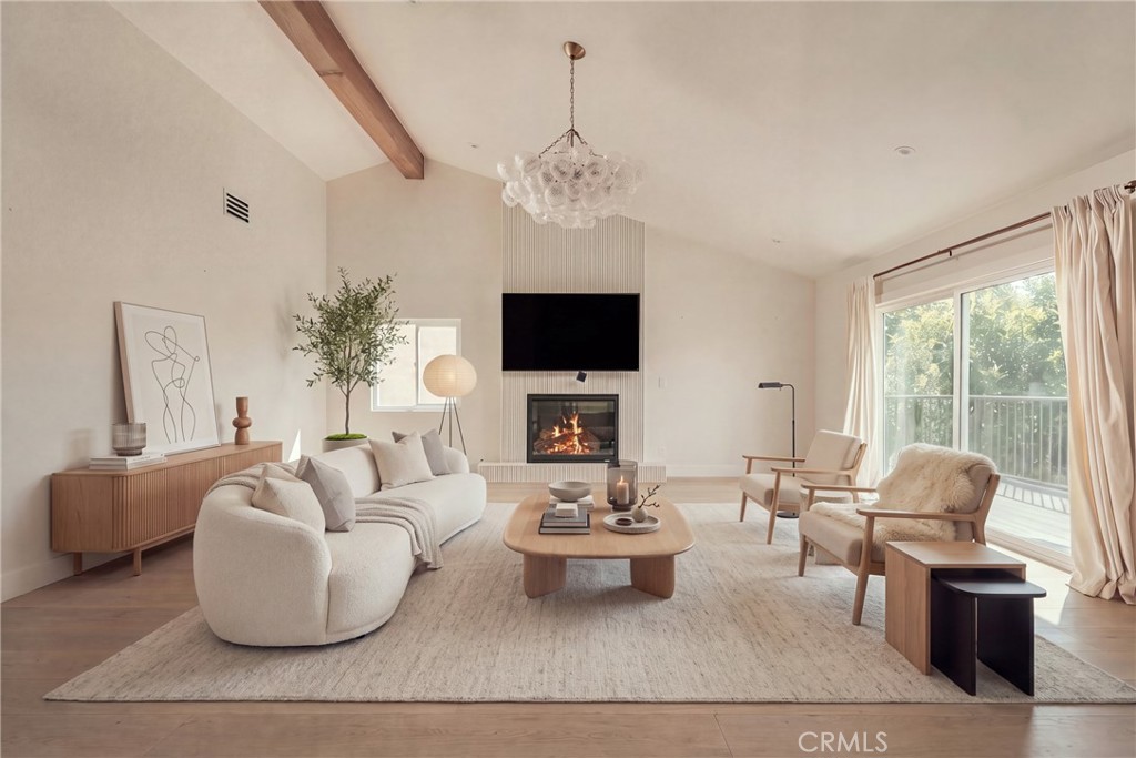 Staged living room with a fireplace, neutral furnishings, and sliding glass doors to a balcony.