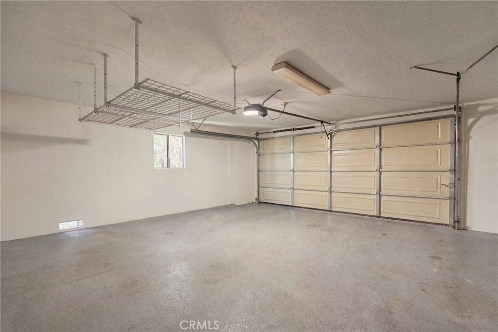 Empty two-car garage with ceiling-mounted storage racks and a wide sectional door.