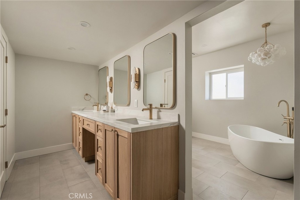 Modern bathroom with a double vanity, natural wood cabinets, and a freestanding soaking tub.