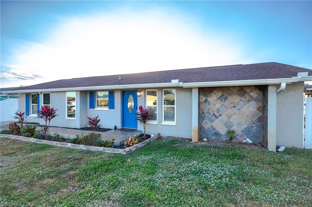 Single-story stucco home with blue entry door, blue shutters, and stone-patterned garage door.