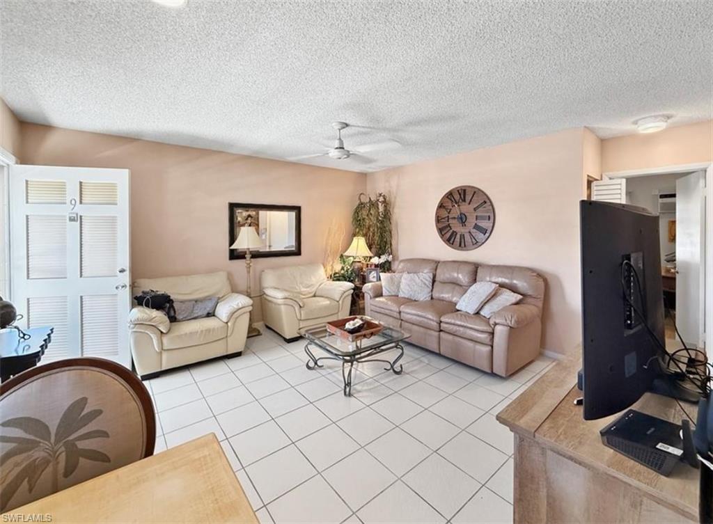 Living room with cream armchairs, beige sofa, and white tile flooring.