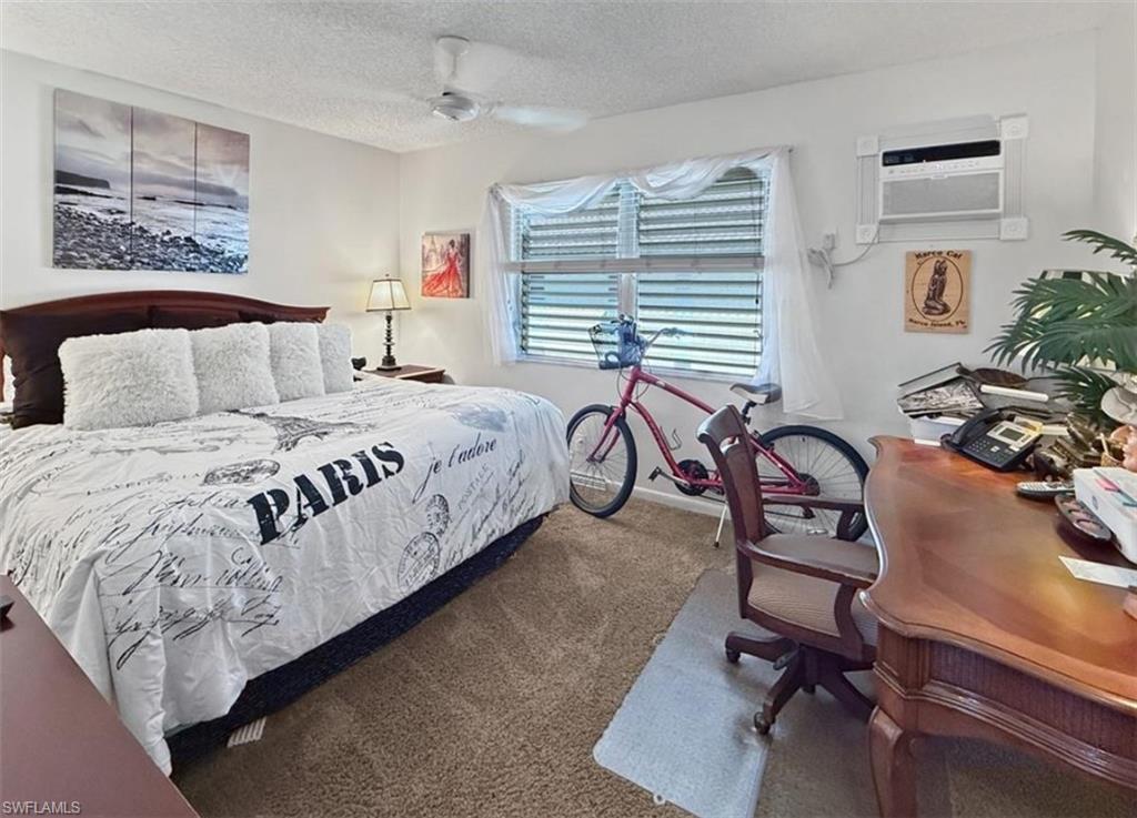 Furnished bedroom with Paris-themed bedding, a pink bicycle, and a wooden desk.
