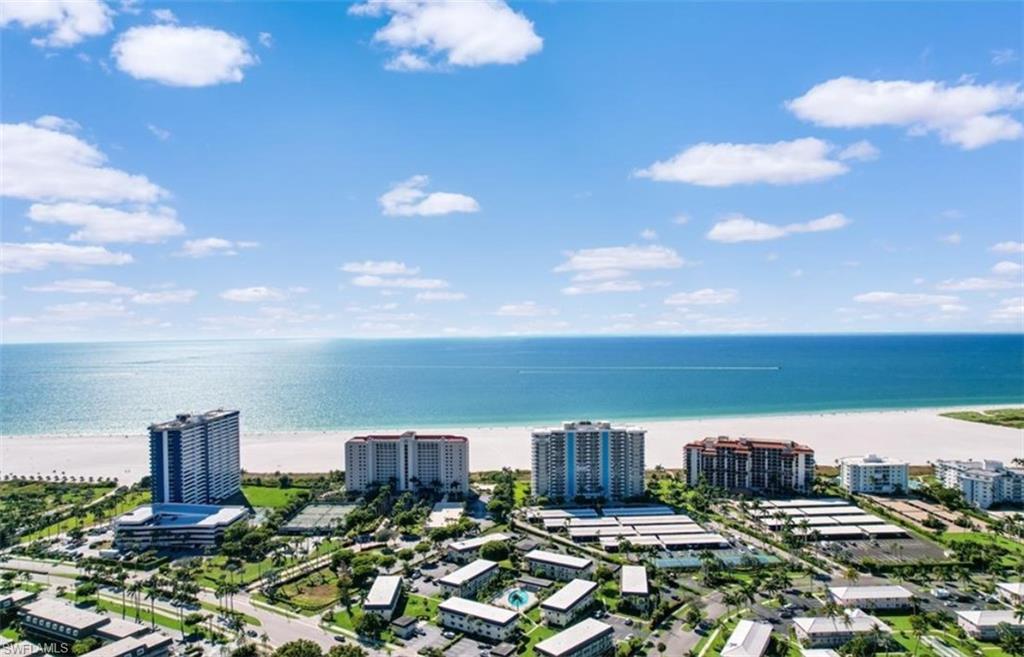 Aerial view of beachfront high-rises and residences along a turquoise Gulf shoreline.
