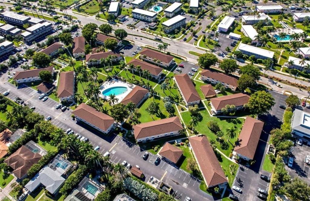 Aerial view of a condominium complex with a turquoise pool and red-tile roofs.