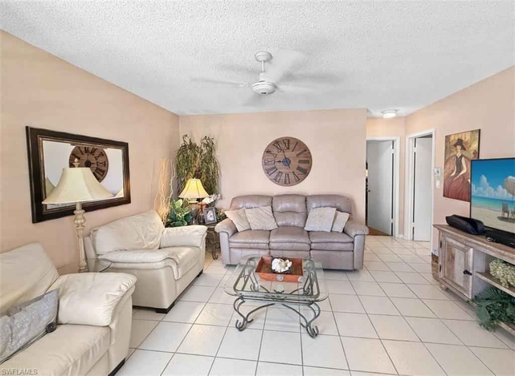 Living room with cream and gray sofas, tiled floors, and a glass coffee table.