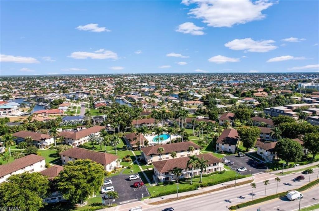 Aerial view of a palm-lined Marco Island neighborhood with canals, red-tile roofs, and a pool.