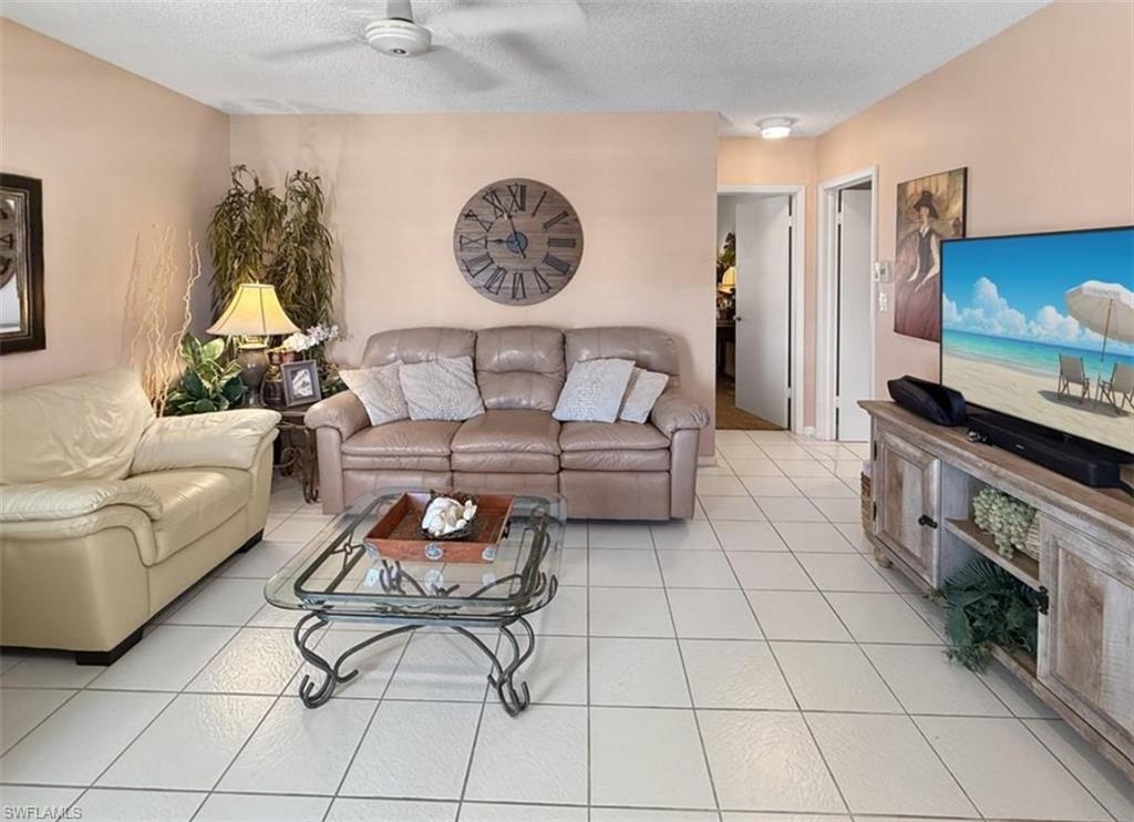 Living room with beige leather sofas, a glass coffee table, and a large Roman-numeral wall clock.