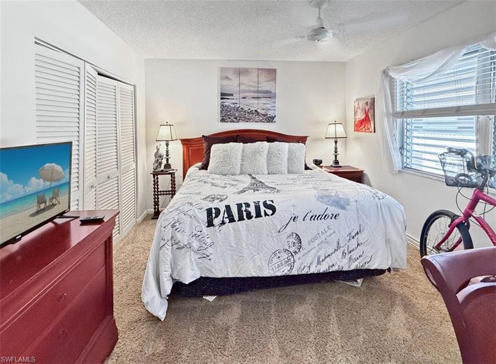 Bedroom with a Paris-themed duvet, dark red wooden furniture, louvered closet doors, and a bright window.