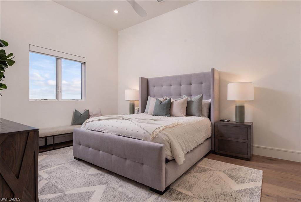 Staged bedroom with a tufted gray bed, matching nightstands, and a large patterned rug.