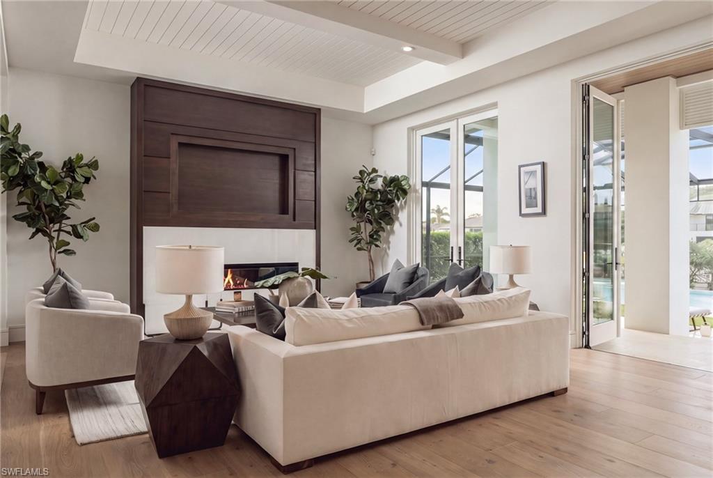 Living room with a dramatic dark wood fireplace wall and glass doors opening to a pool area.