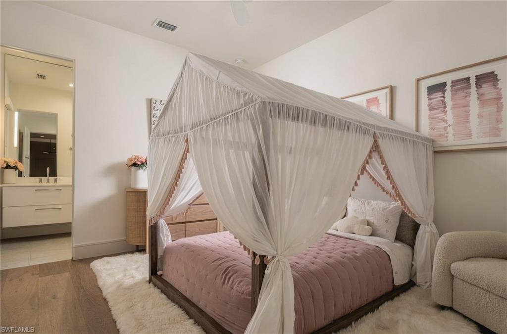 Bedroom with a pink quilted bed beneath a white canopy and an ensuite bathroom.