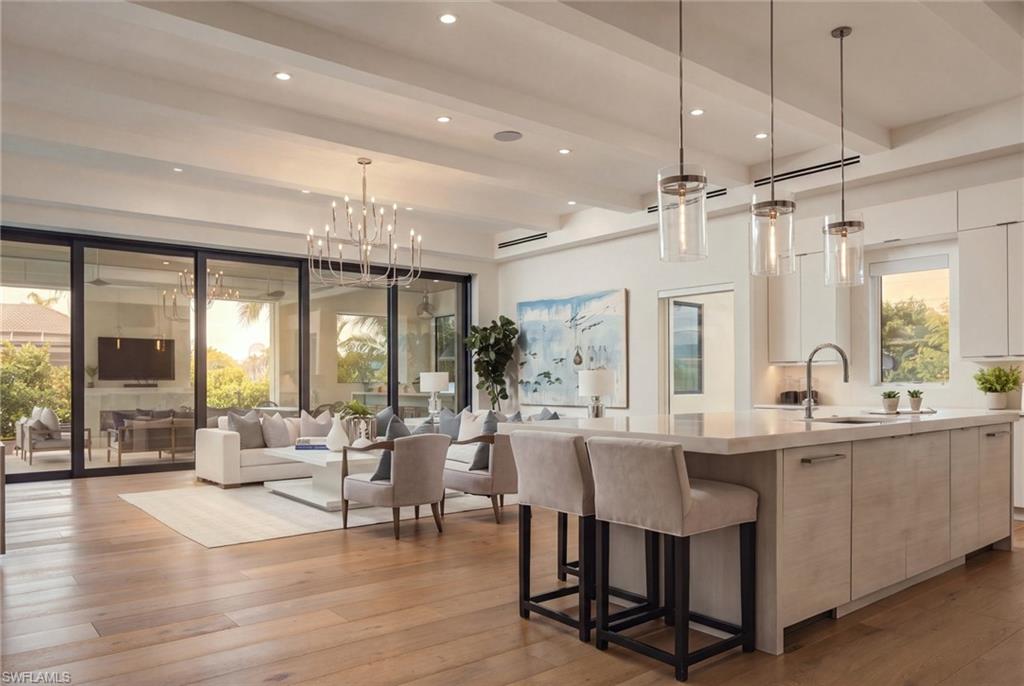 Open-plan kitchen and living room with a large island, wood floors, and sliding glass doors.