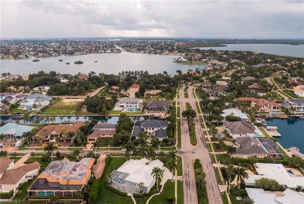 Aerial view of waterfront homes and canals along a tree-lined road on Marco Island.