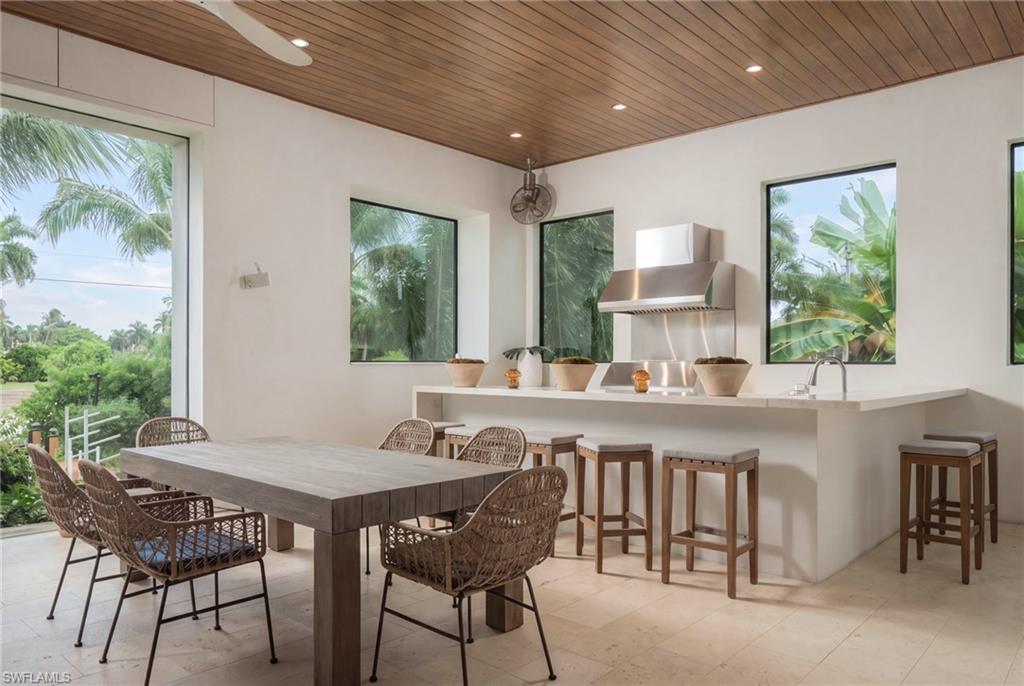 Dining area with a large table and woven chairs beside a kitchen counter with bar stools.