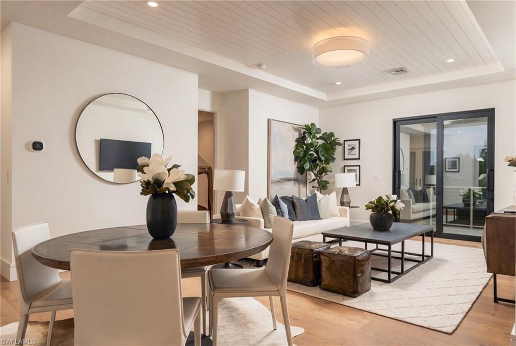 Staged dining and living room with a round table, white sofa, and sliding glass doors.