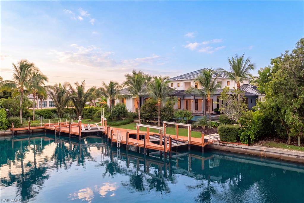 Waterfront home with a long dock and palm-lined landscaping along a canal.