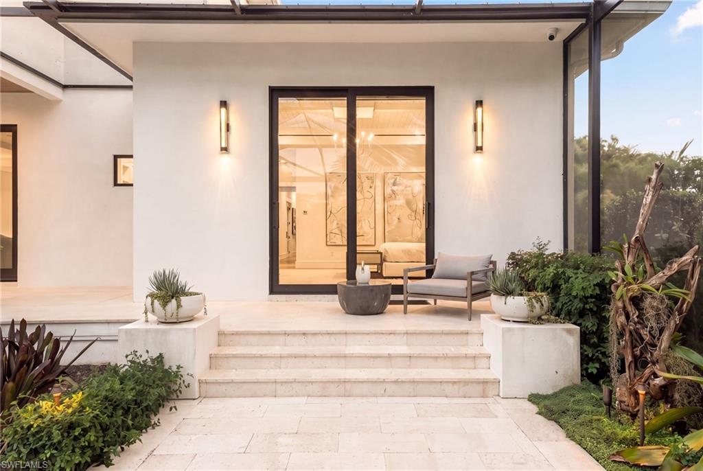Patio entrance with broad stone steps, glass doors, and a cushioned chair.
