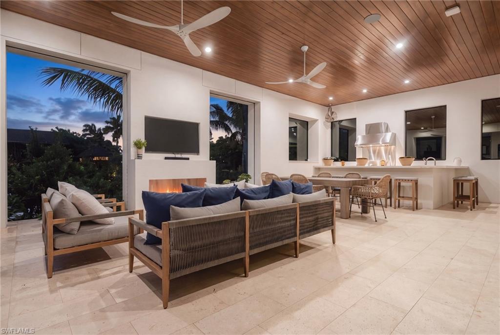 Living room with a wood-plank ceiling, fireplace, and open dining and kitchen area.