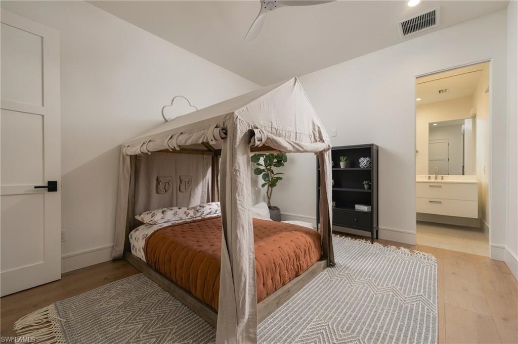 Bedroom with a draped canopy bed, geometric area rug, and doorway to an ensuite bathroom.