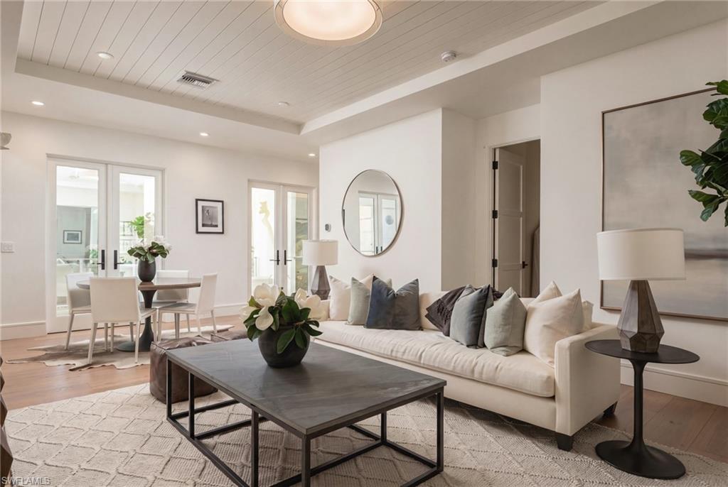 Living room with a white sectional sofa, dark coffee table, and dining area by glass doors.