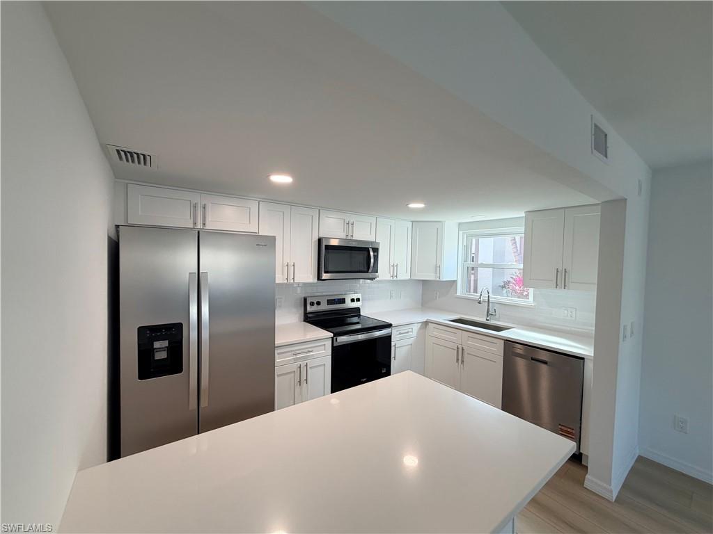 Kitchen with white shaker cabinets, a large island, and stainless steel appliances.