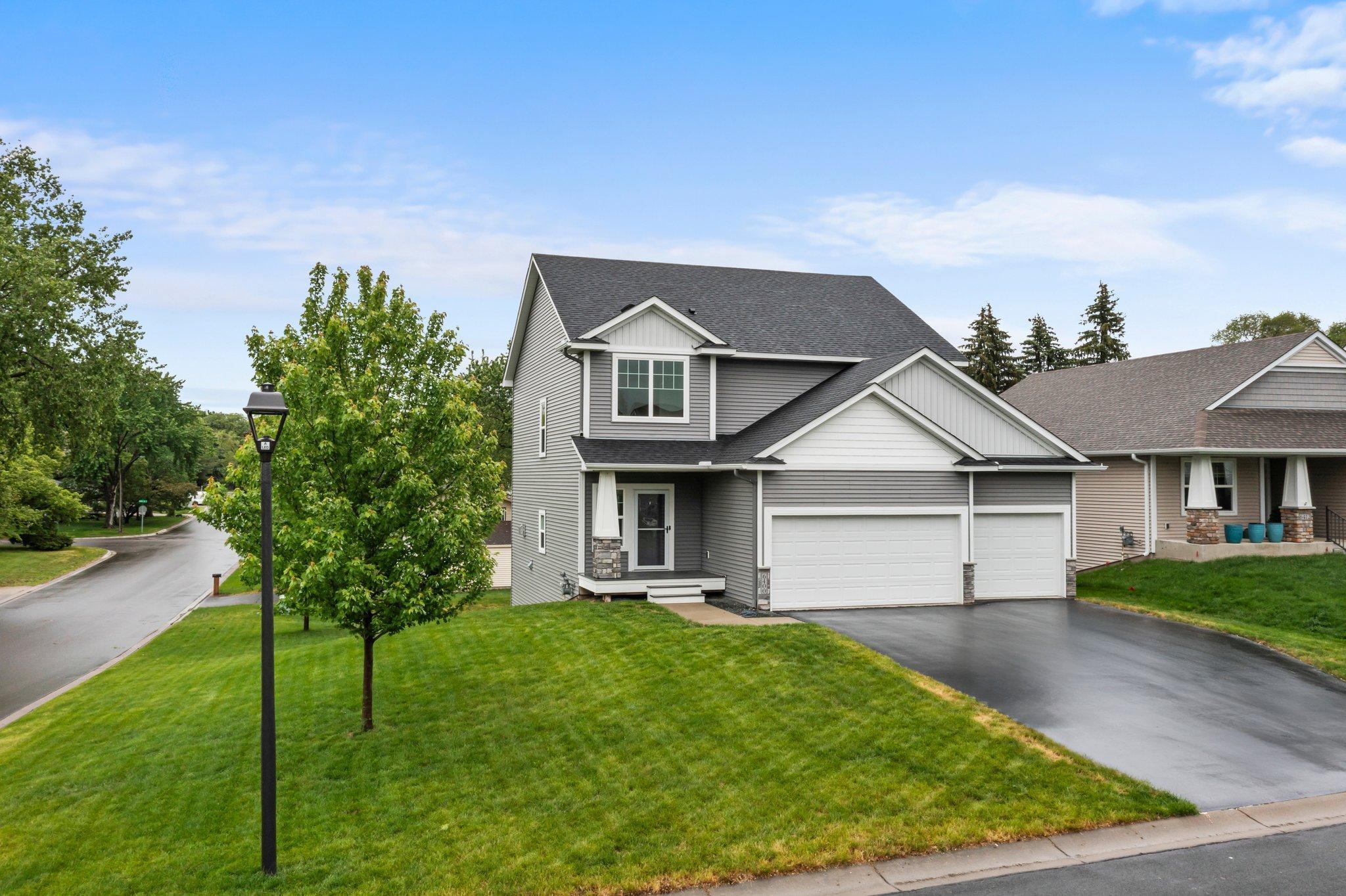 Gray two-story home with white trim, attached two-car garage, and a broad green front lawn.