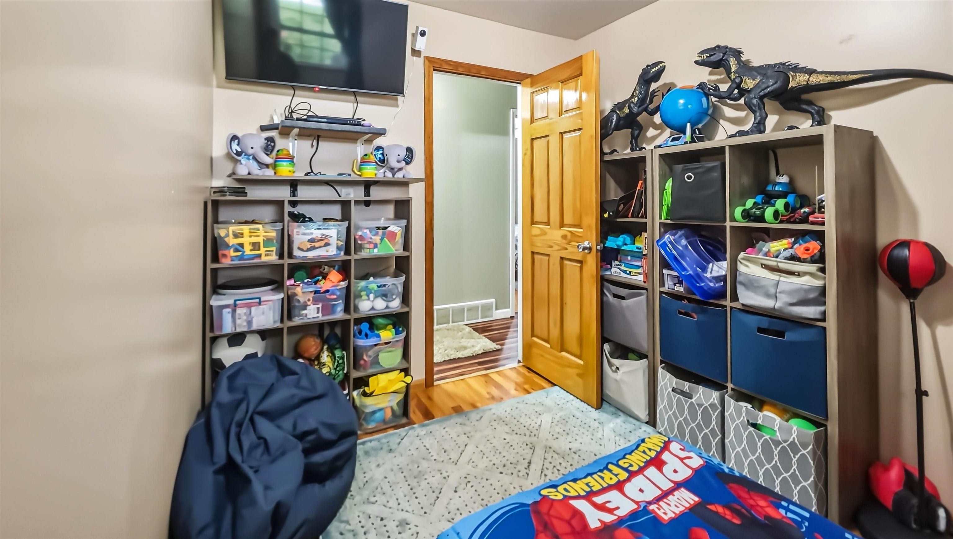 Playroom with toy-filled cubbies, dinosaur figures, and a Spider-Man mat.