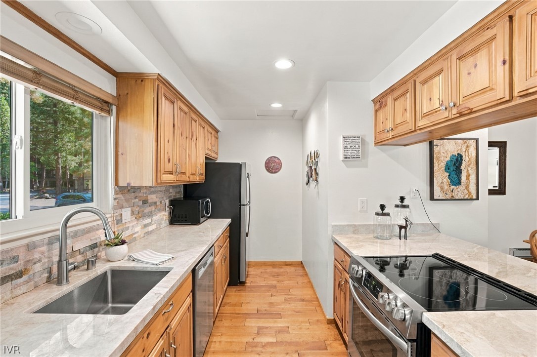 Kitchen with honey-colored wood cabinets, stone counters, and stainless steel appliances.