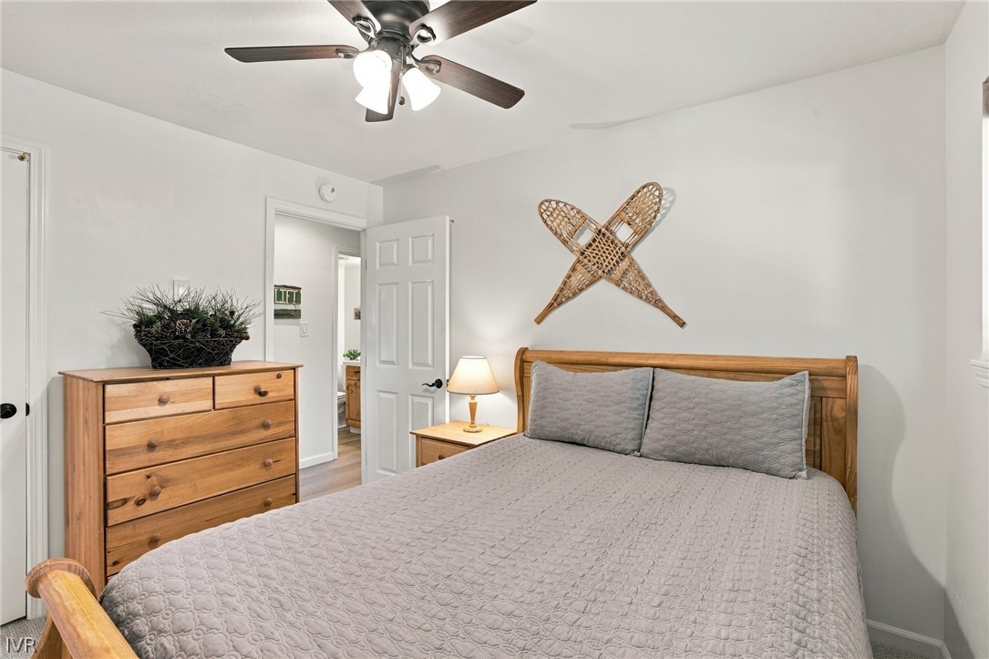 Furnished bedroom with a wooden bed, gray quilt, matching dresser, and crossed wooden snowshoes above the headboard.