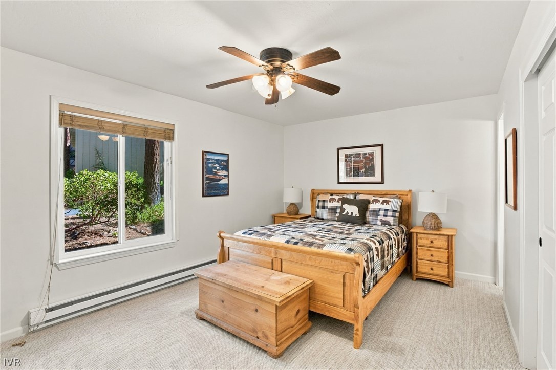 Bedroom with a wooden bed, matching nightstands, and a window overlooking shrubs.