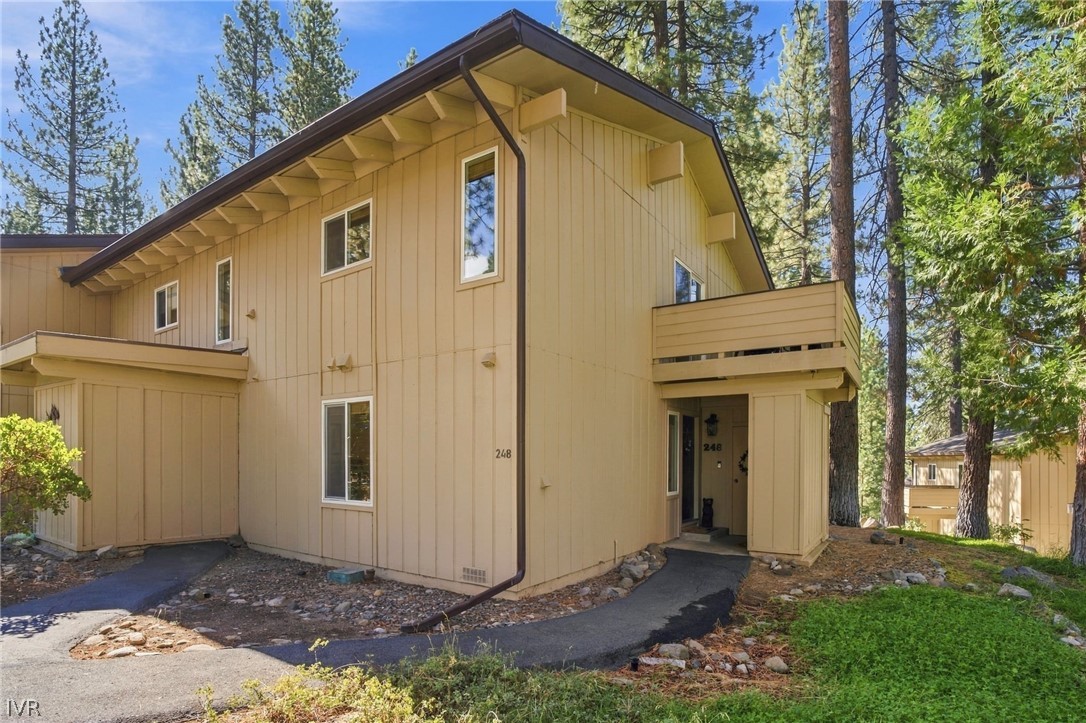 Exterior of 321 Ski Way unit 248, a tan-sided home among pine trees.