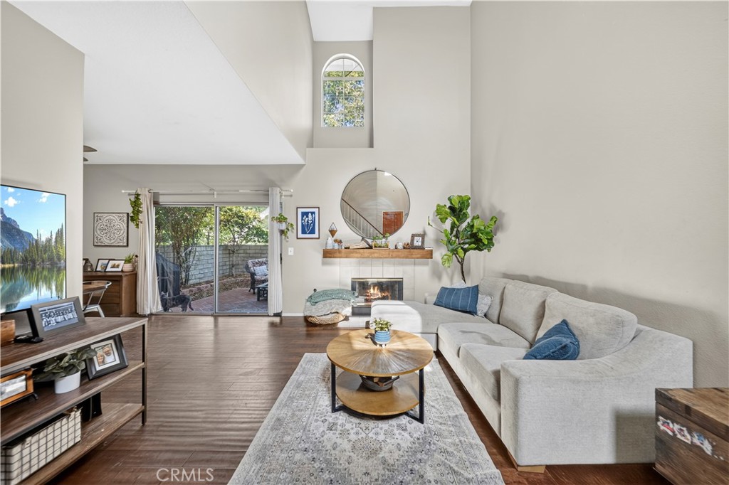 Living room with a vaulted ceiling, fireplace, gray sectional, and sliding doors to a patio.