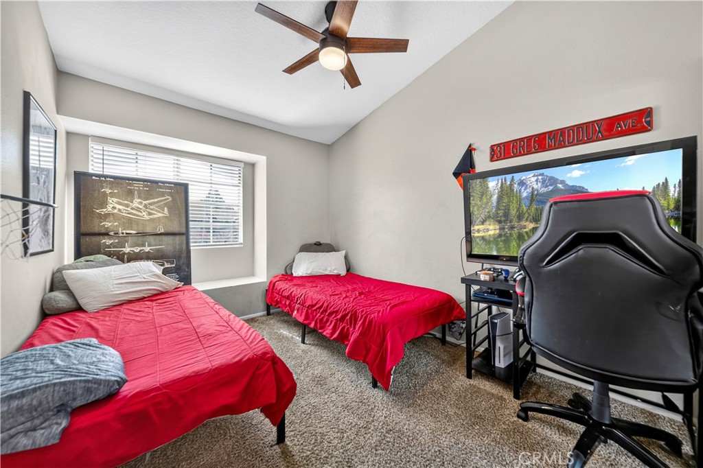 Bedroom with two red-covered twin beds and a computer gaming setup.