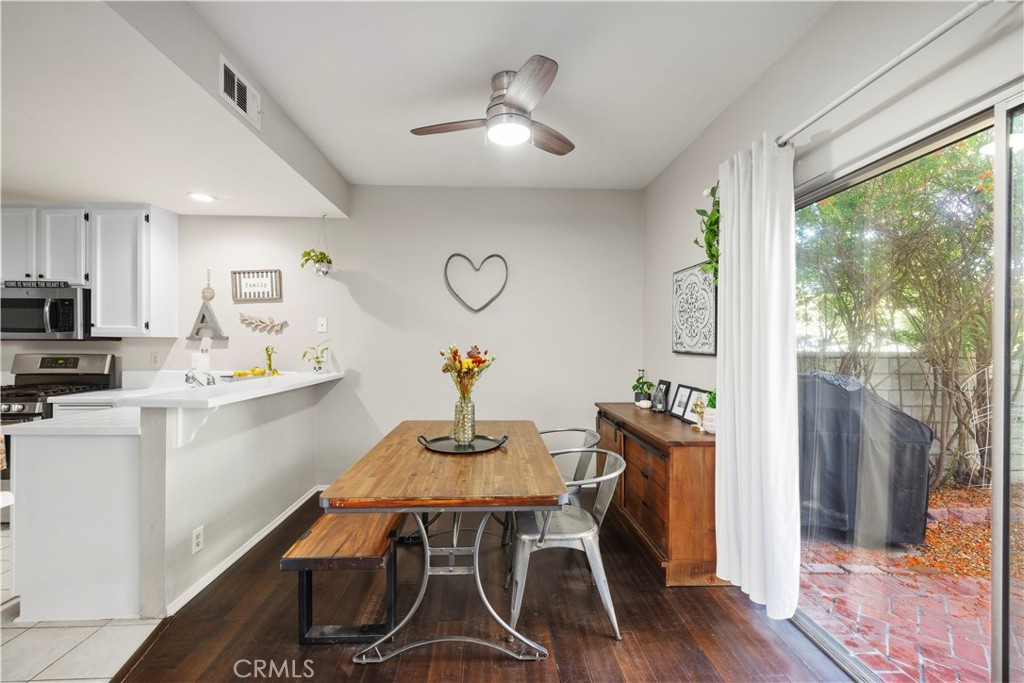 Dining area with a wooden table beside an open kitchen and sliding glass door to a brick patio.