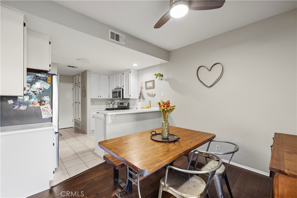 Kitchen and dining area with white cabinets, a breakfast counter, and a wooden table.