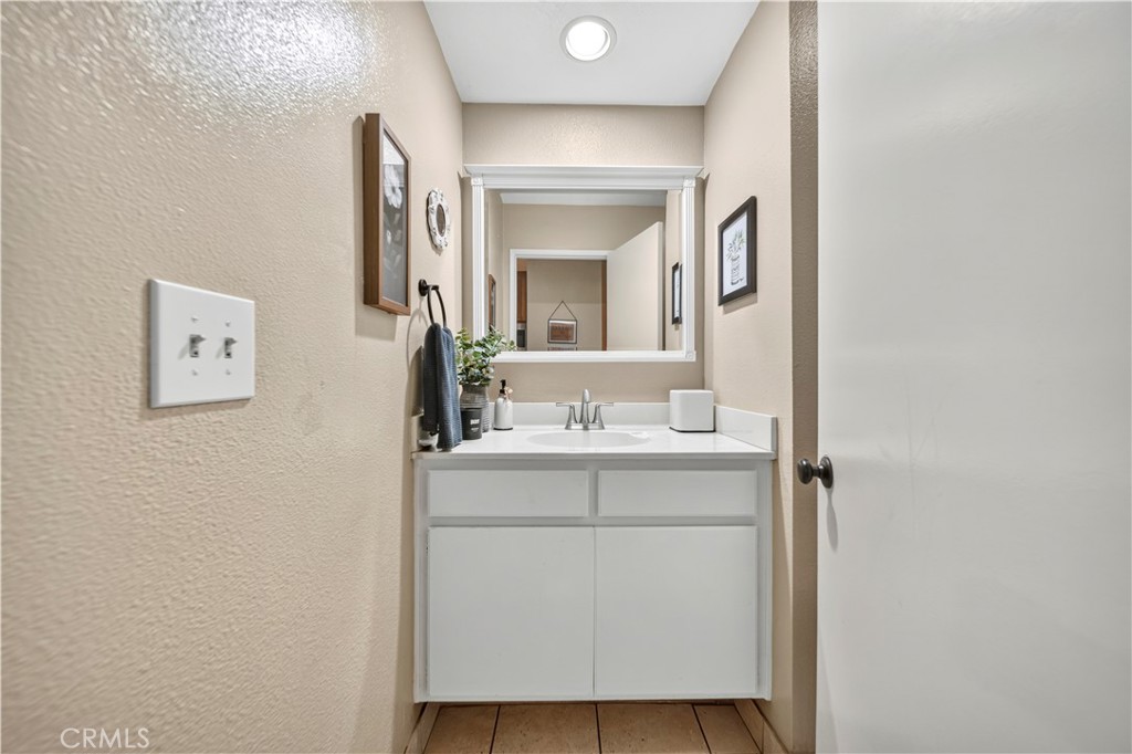 Bathroom vanity with a white cabinet and sink beneath a framed mirror.