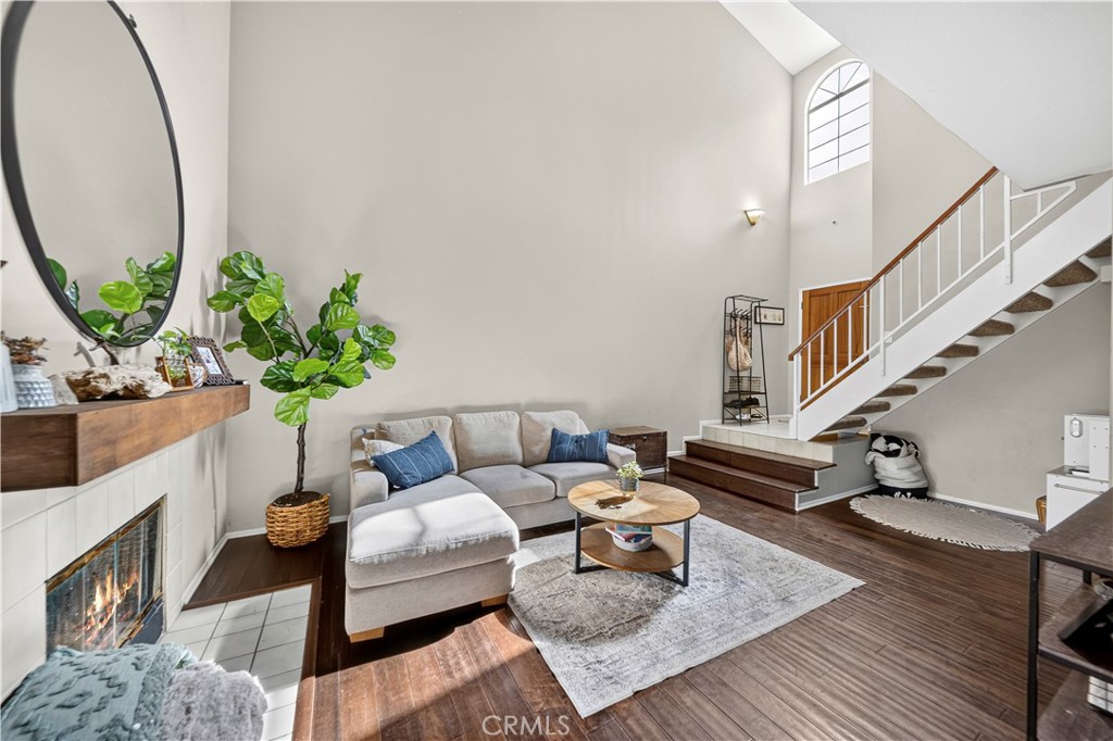 Living room with a vaulted ceiling, white sectional sofa, fireplace, and staircase.