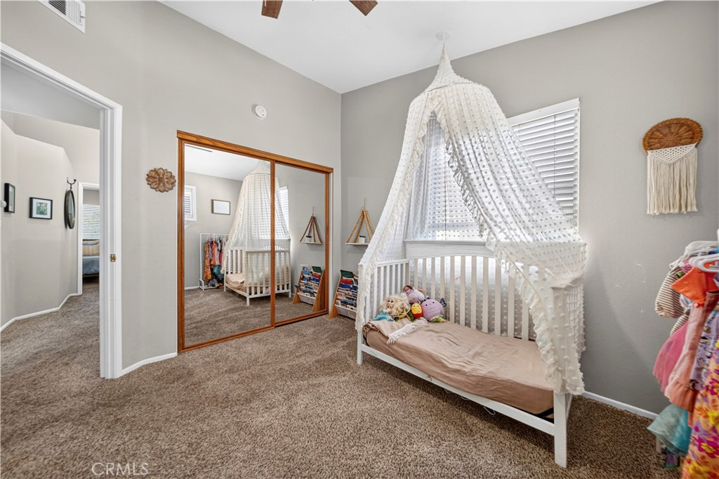 Bedroom with a white canopy bed, mirrored closet doors, and beige carpet.