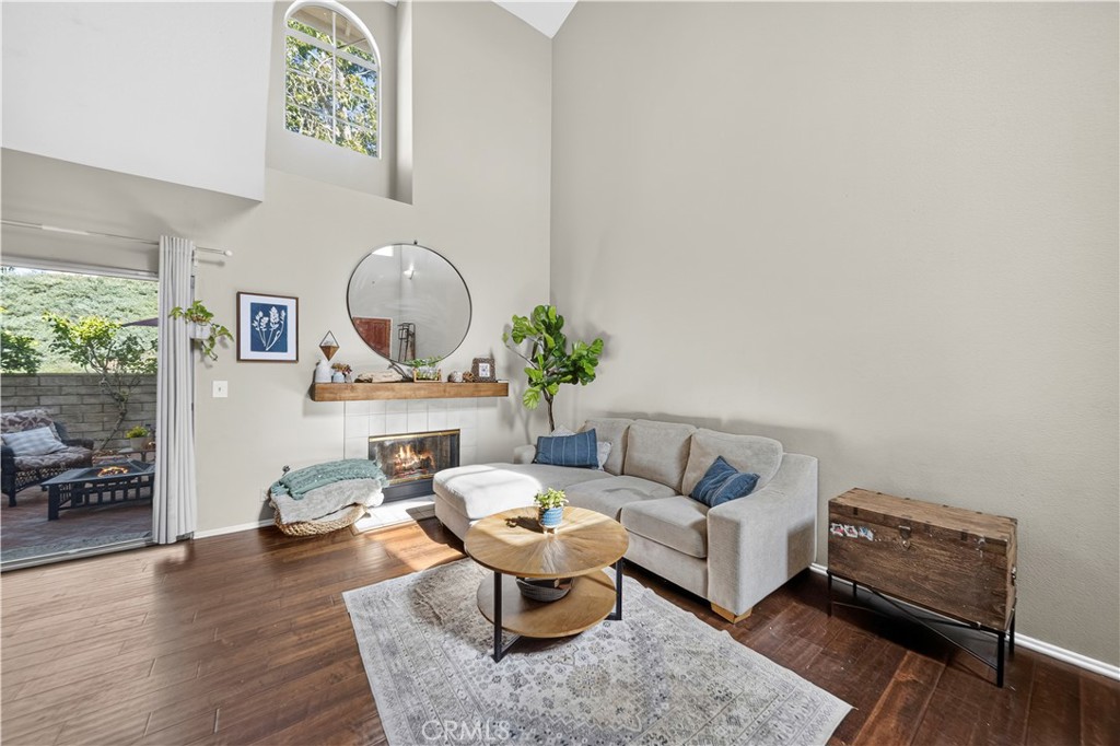 Living room with a high ceiling, fireplace, light sectional, and sliding glass door to a patio.