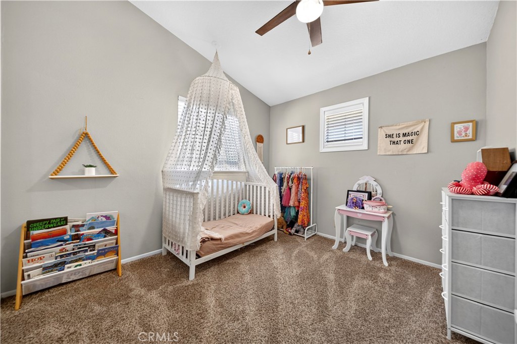 Nursery with a white canopy bed, children’s books, and a small pink table and chairs.